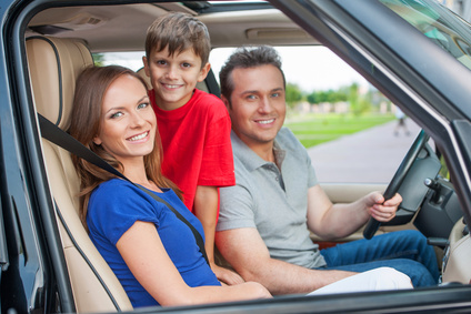 Family with one kid is travelling by car, smiling and looking at
